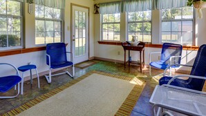 A sunlit room with large windows, blue chairs, a white table, and a wooden bench. - Vintage Chipley Getaway on Large Private Property (Chipley)