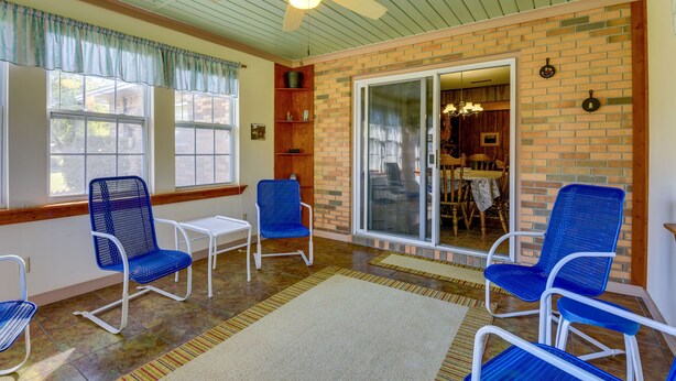 A room with a brick wall, a ceiling fan, and a large sliding glass door leading to a dining area. - Vintage Chipley Getaway on Large Private Property (Chipley)