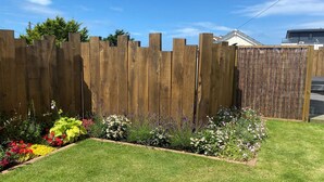Une clôture en bois avec un jardin devant.