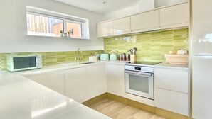 Une cuisine moderne avec des meubles blancs, un four à micro-ondes, un grille-pain et un dosseret de carrelage vert.