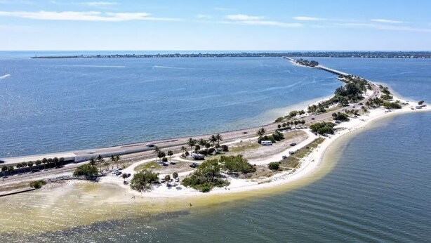 An aerial view of a coastal area with a beach, a road, and a distant shoreline. - Come relax, restore and play at this calming fun retreat! Location! Pool, BBQ. (Cape Coral)