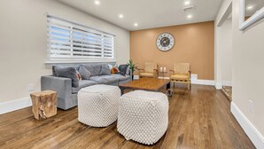 A living room with a grey sofa, wooden coffee table, and two white poufs.