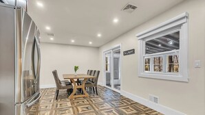 A kitchen with a dining table, chairs, a refrigerator, and a window with a view.