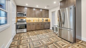 A modern kitchen with built-in appliances, wooden cabinets, and a patterned floor.