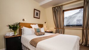 A neatly made bed with a wooden headboard, a bedside table with a vase of flowers, and a window with curtains. - ROOFTOP 3BR PH-INDOOR SAUNA IN DUBLIN (Dublin)