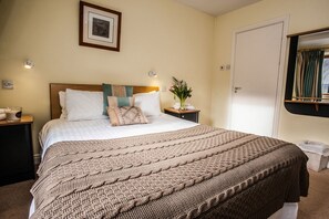 A neatly made bed with a brown knitted blanket, a bedside table with a vase of flowers, and a framed picture on the wall. - ROOFTOP 3BR PH-INDOOR SAUNA IN DUBLIN (Dublin)