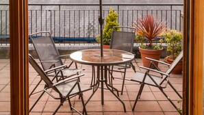 An open patio with a round table and chairs, a large umbrella, and potted plants. - ROOFTOP 3BR PH-INDOOR SAUNA IN DUBLIN (Dublin)