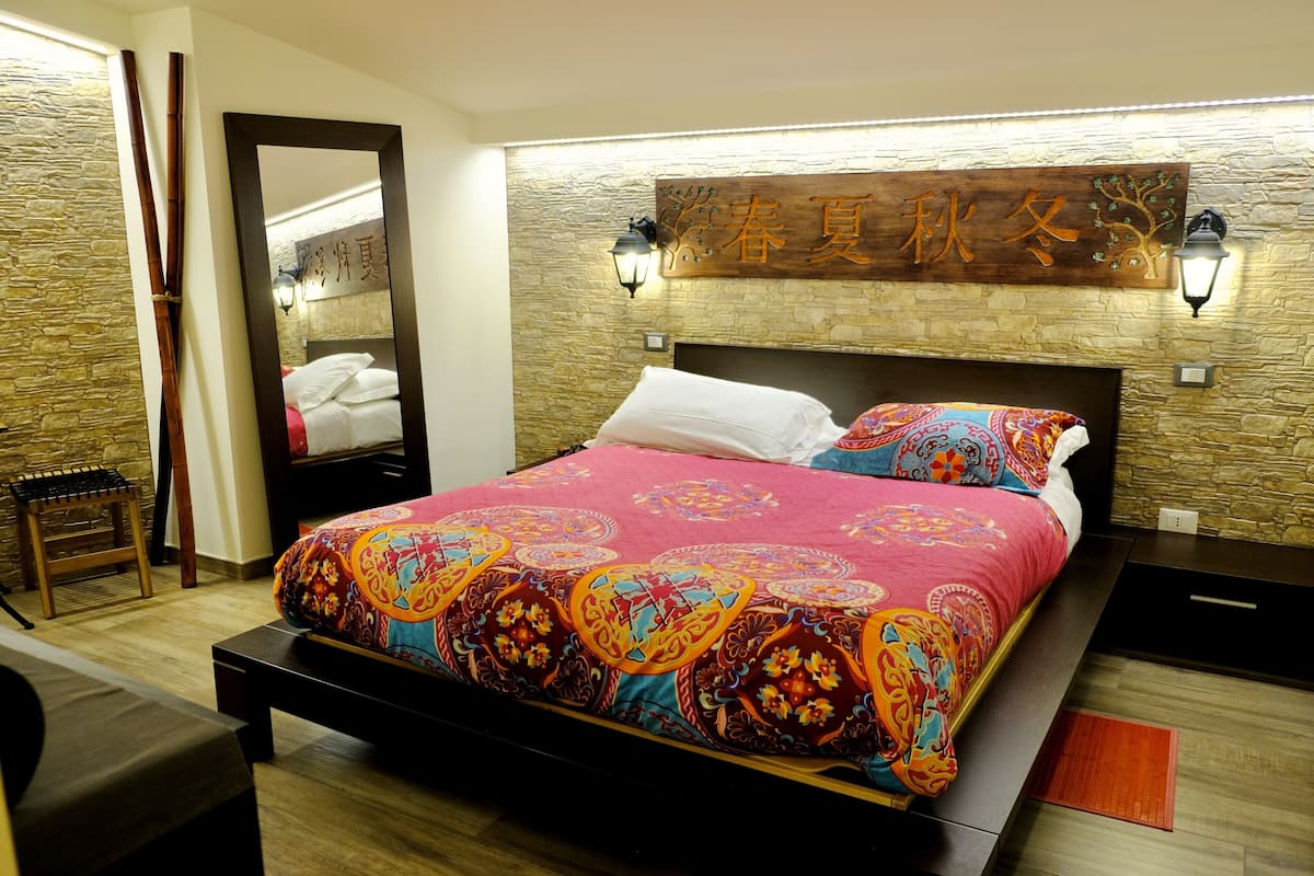A bedroom with a bed, wooden headboard, stone wall, and a decorative sign.