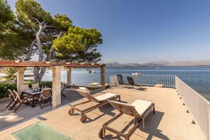 An outdoor patio with a pergola, seating area, and a view of the sea. - Villa Me Chabot (Alcúdia)
