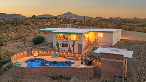 Une maison à deux étages avec une piscine, un espace salon extérieur et une vue sur les montagnes.