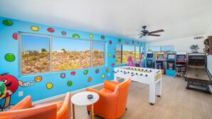 Une pièce dotée d’un baby-foot, de décorations murales colorées et offrant une vue sur un paysage désertique grâce à de grandes fenêtres.