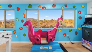 Une pièce avec une grande fenêtre, une structure de jeu rose et une table de baby-foot.