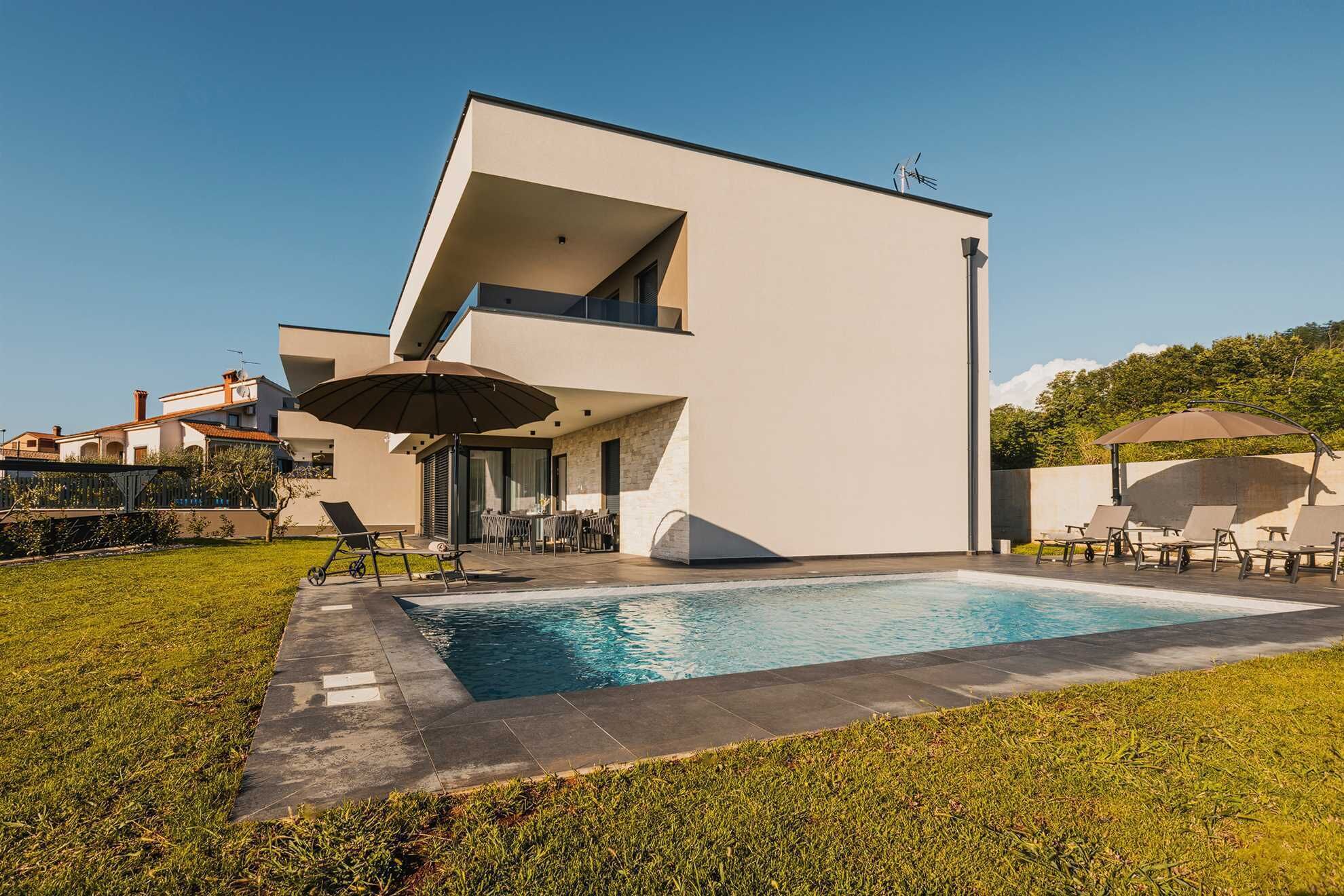 A modern two-story house with a swimming pool, outdoor seating, and a clear sky.