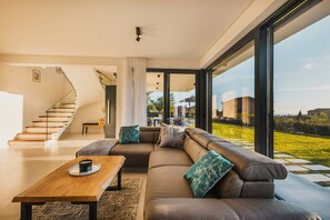 A modern living room with a leather sofa, wooden coffee table, and a staircase leading to an upper floor.