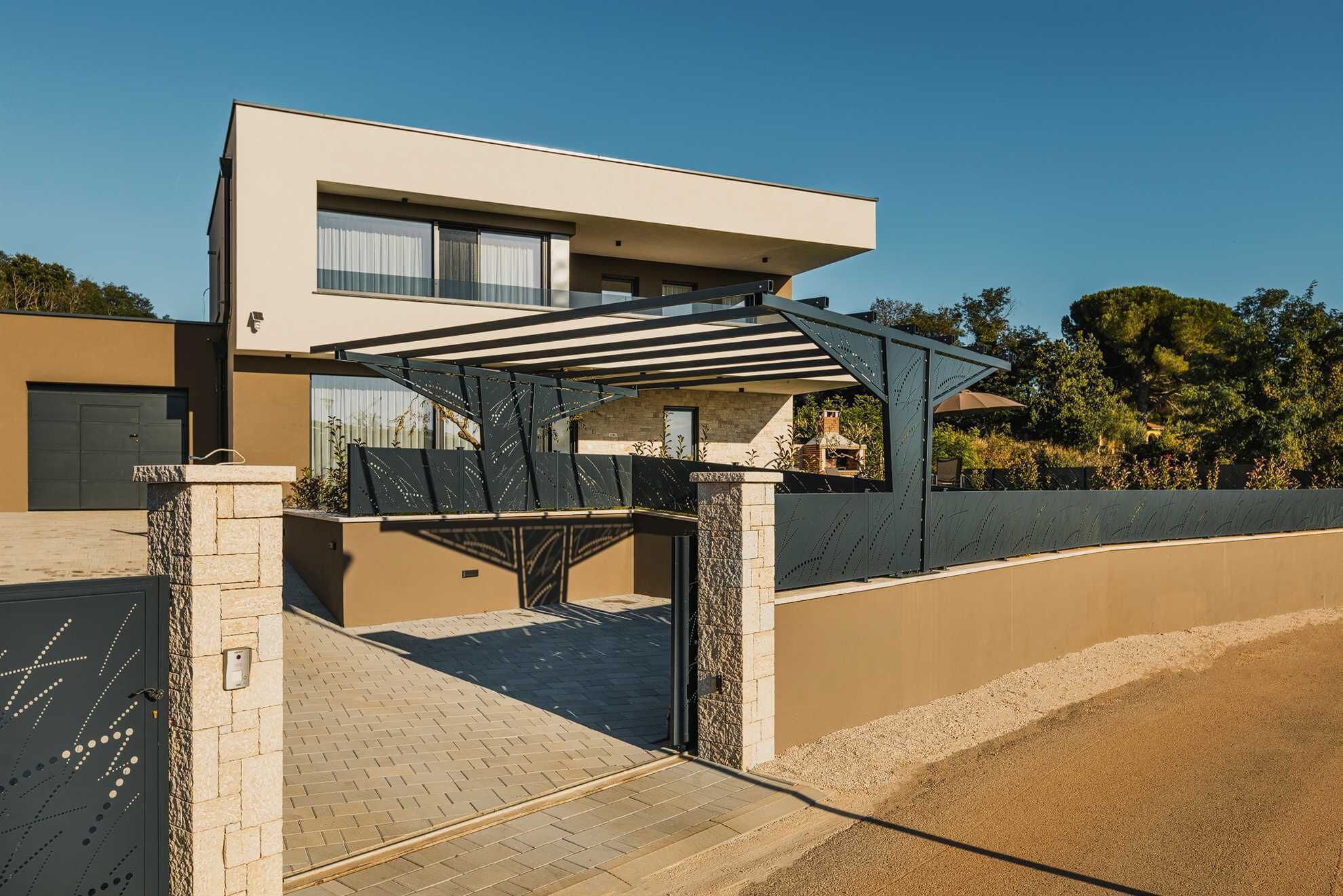 Une maison moderne à deux étages, dotée d’une allée couverte et d’un mur en pierre.