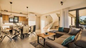 A modern living room with a sofa, coffee table, and dining area with chairs. There is a staircase leading to another level. - Villa Angelina - Idyllic 4 BD villa for 8 with pool close to Porec (Kaštelir)