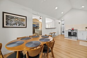 A modern kitchen with white cabinets, a stainless steel oven, and a red kettle on the countertop.