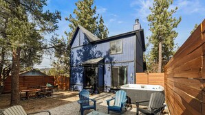 Una casa azul con una chimenea, mobiliario de exterior y un jacuzzi.