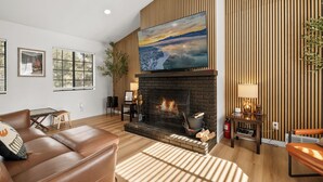Una sala de estar con chimenea, un televisor de pantalla plana grande y una pared de acento de madera.