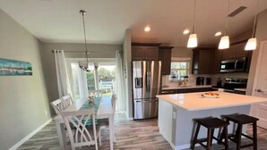 A modern kitchen with a central island, stainless steel appliances, and pendant lighting. - Waterfront Gem, kayak, fish, restaurants close by (Port Charlotte)