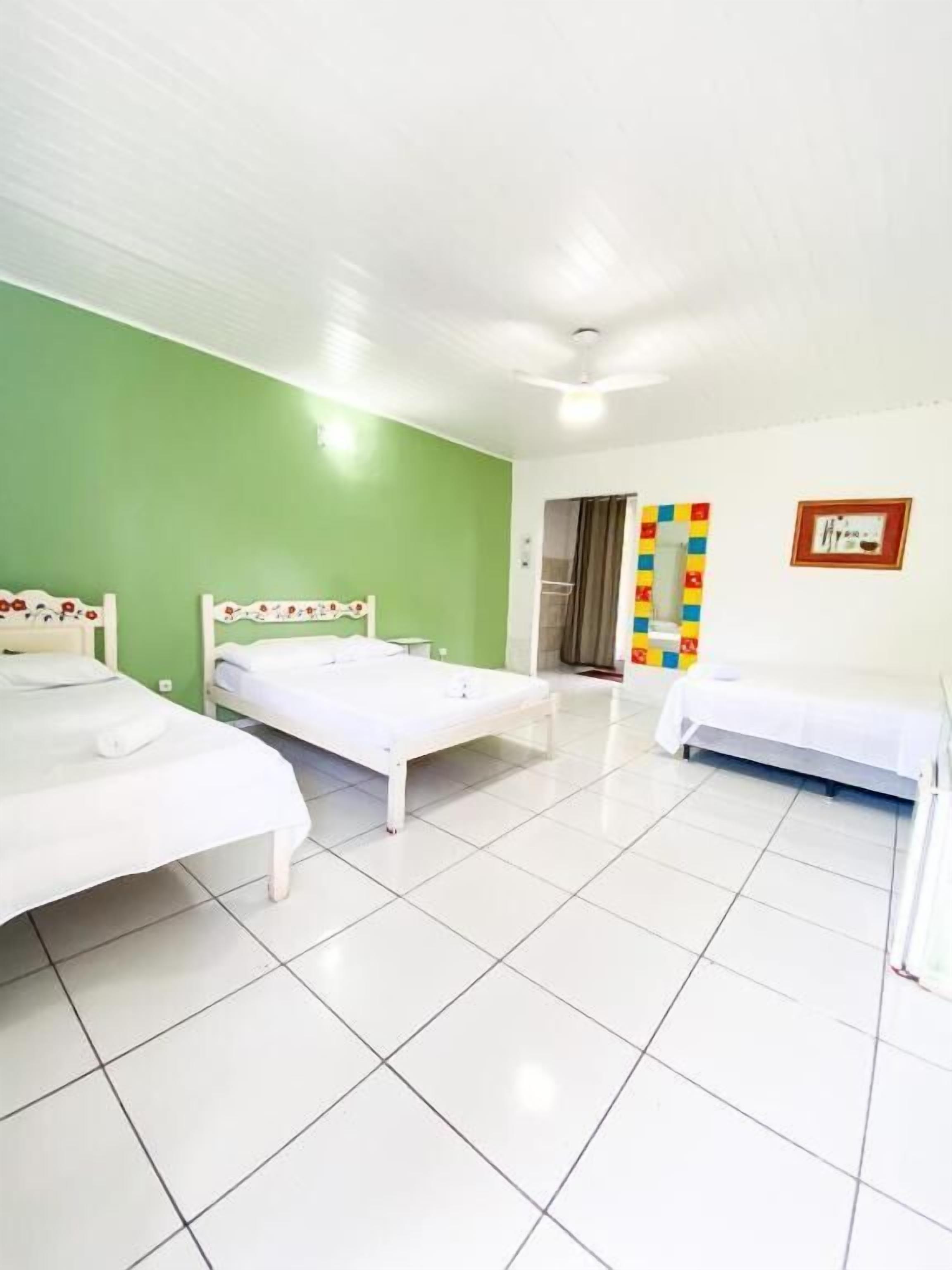 A room with two beds, a green wall, and a tiled floor.