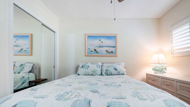 Une chambre à coucher avec un lit, une table de chevet, une lampe et deux tableaux encadrés accrochés au mur.