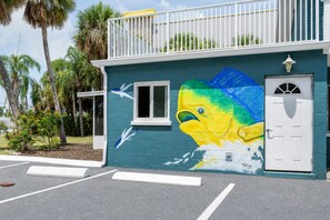 Un edificio con un murale raffigurante un pesce, una porta bianca e un balcone.