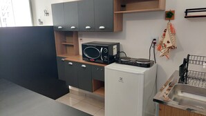 Eine kleine Küche mit einer Mikrowelle, einem Kühlschrank und einem Spülbecken.