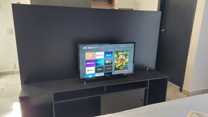 Ein Flachbildfernseher auf einer schwarzen Unterhaltungsanlage in einem Hotelzimmer.