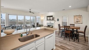Een moderne keuken met een groot kookeiland, een eethoek met houten stoelen en een open haard.