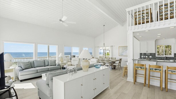 A spacious living area with a large sofa, dining table, and kitchen area with bar stools. - 446 Tarpon Blvd (Fripp Island)