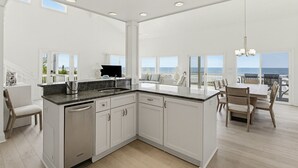 A modern kitchen with a central island, white cabinetry, and a view to the outside. - 446 Tarpon Blvd (Fripp Island)