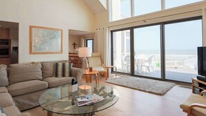 A spacious living room with a large glass coffee table, a sofa, and a television. - 458 Tarpon Blvd (Fripp Island)