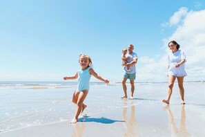 Eine Szene am Strand, eine Familie spaziert im Sand.