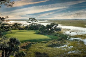 Un campo de golf con un cuerpo de agua y árboles.