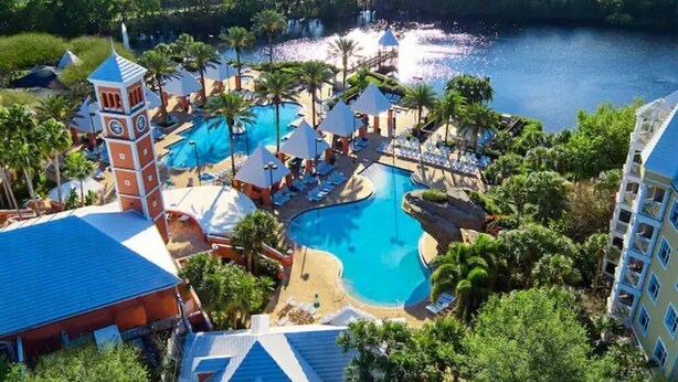 Et resort med flere swimmingpools, palmer og et klokketårn.