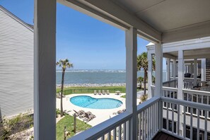 A pool with a view of the ocean, a deck with chairs, and a railing. - 709 Ocean Cottage (Fripp Island)