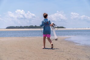 Une personne marchant sur une plage de sable et tenant un filet de pêche.