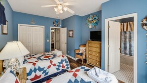A bedroom with two beds, a ceiling fan, a television, and a door leading to another room. - 23 Davis Love Drive (Fripp Island)