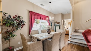 A dining area with wicker furniture, a chandelier, and a red curtain. - 23 Davis Love Drive (Fripp Island)
