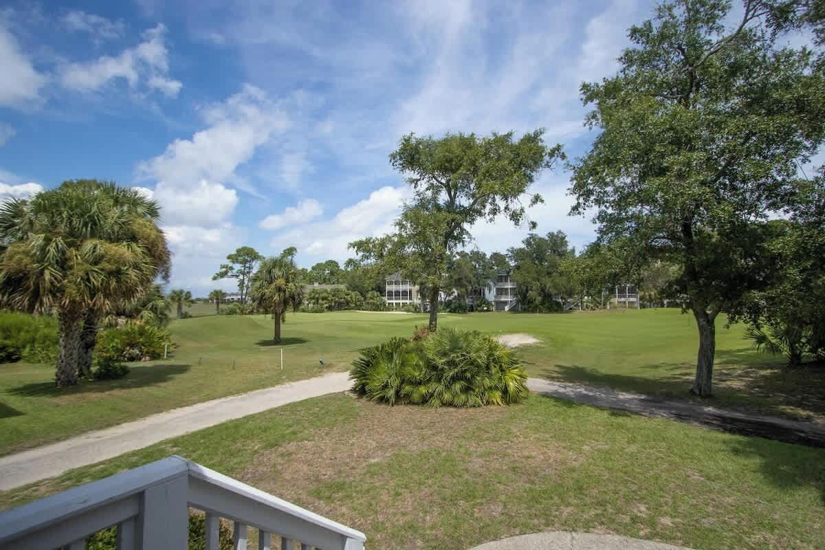 Ein Golfplatz mit einem Weg, Bäumen und einem Gebäude im Hintergrund.