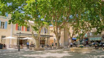 Un espace de café en plein air, avec des tables et des chaises, entouré d’arbres et de bâtiments.