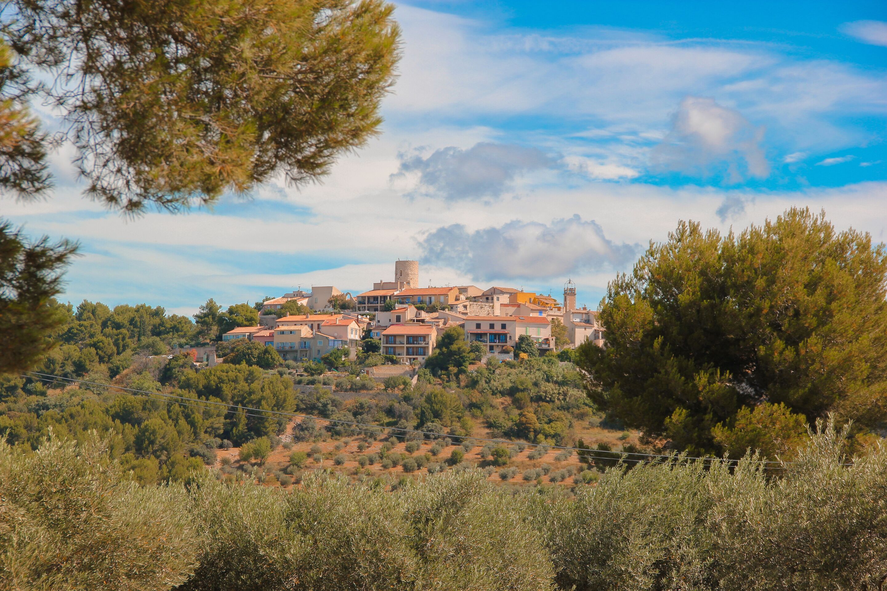 Un paese collinare con edifici, alberi e cielo sereno.