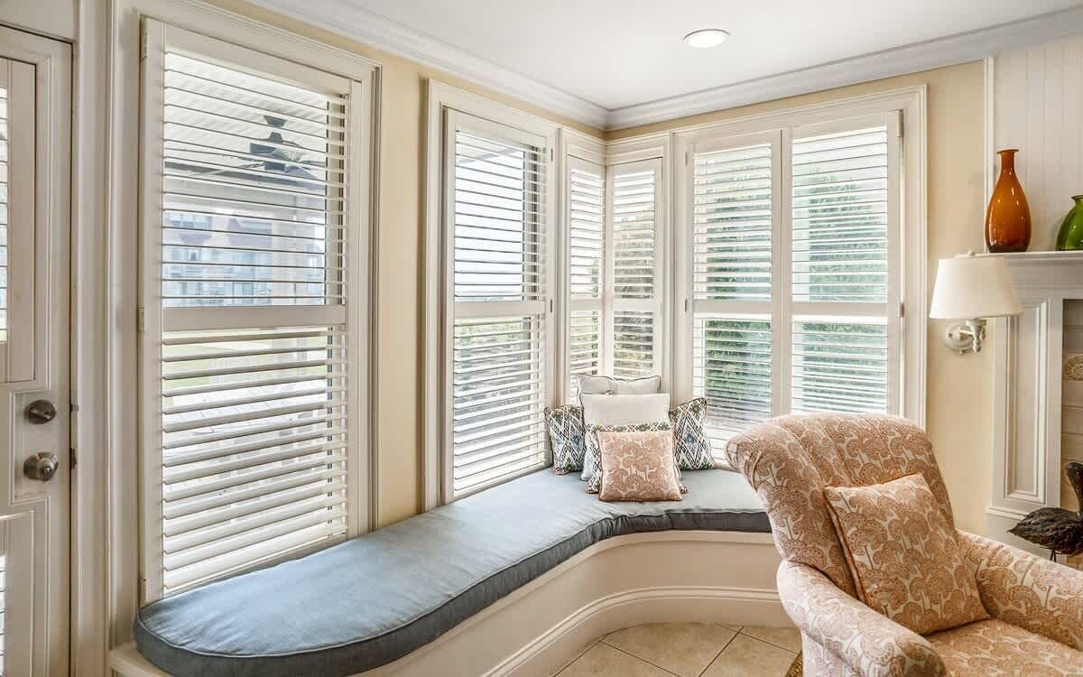 Ein Zimmer mit Erker und einer Sitzgelegenheit, einer gepolsterten Bank und einem gemusterten Sessel.