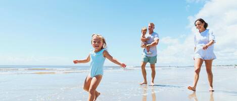 A beach scene with a family walking on the sand.