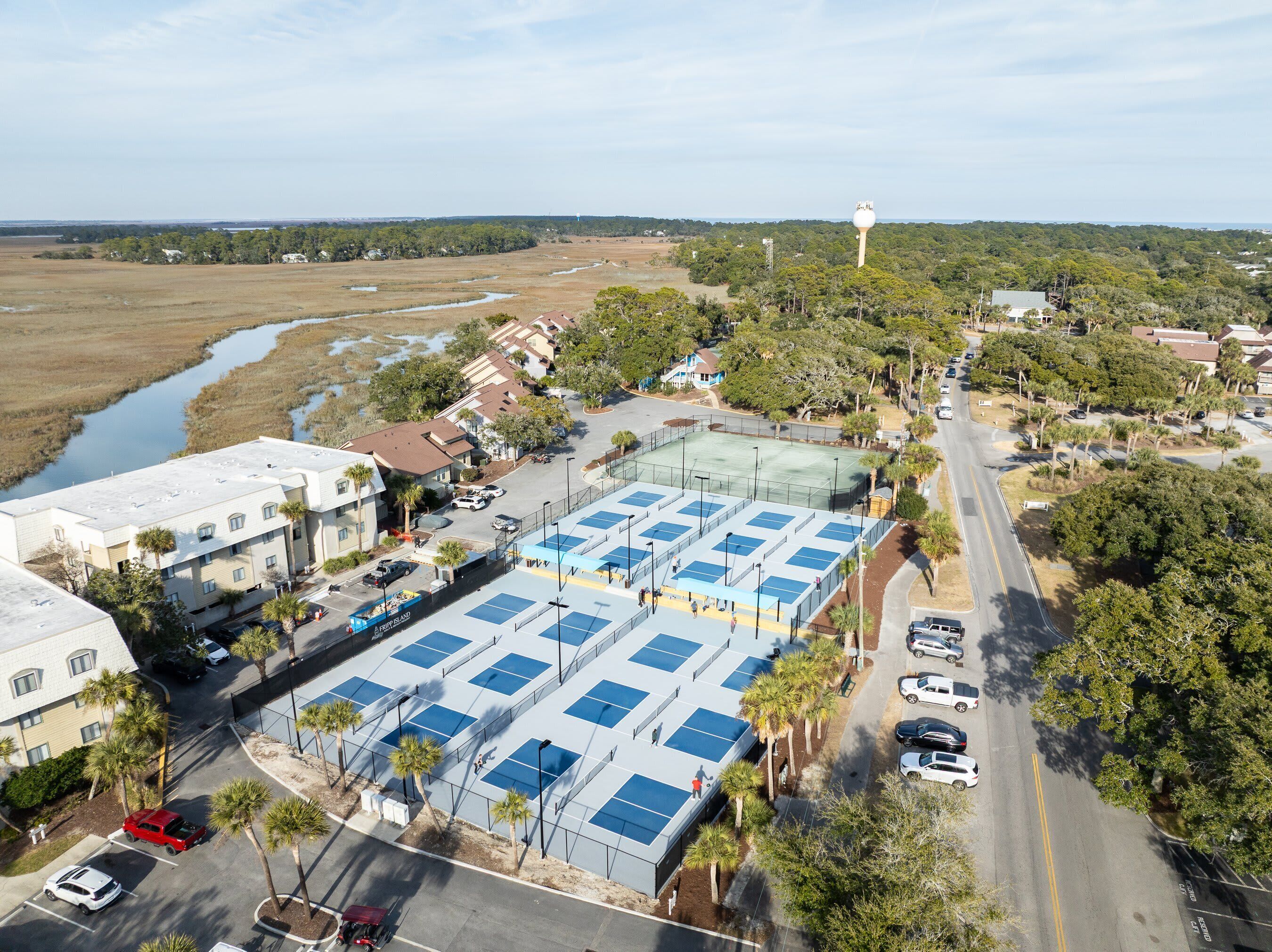 An aerial view of a residential area with a large parking lot, multiple buildings, and a river in the background.