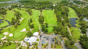 An aerial view of a golf course with multiple greens, sand bunkers, and a prominent tower structure. - 271 Deer Lake Drive (Fripp Island)