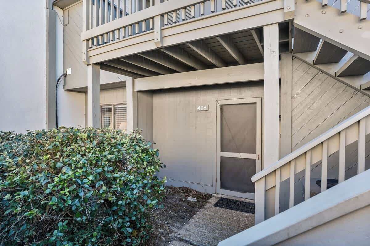 Un immeuble avec une porte portant un numéro, un escalier et un petit arbuste.
