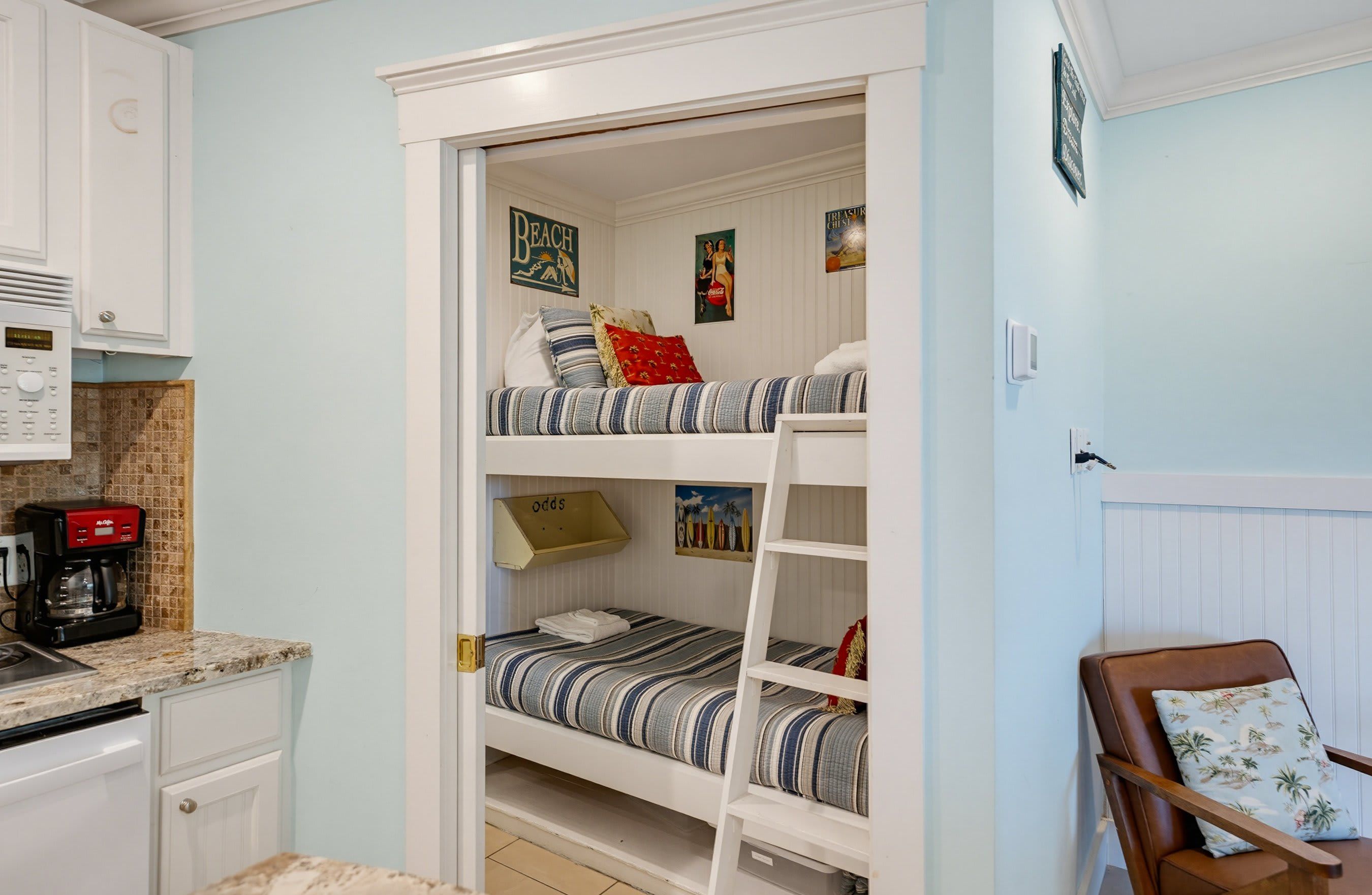 A compact room with bunk beds, a kitchenette, and a small seating area.