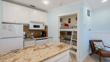 A kitchen with white cabinets, a microwave, a sink, and a granite countertop.